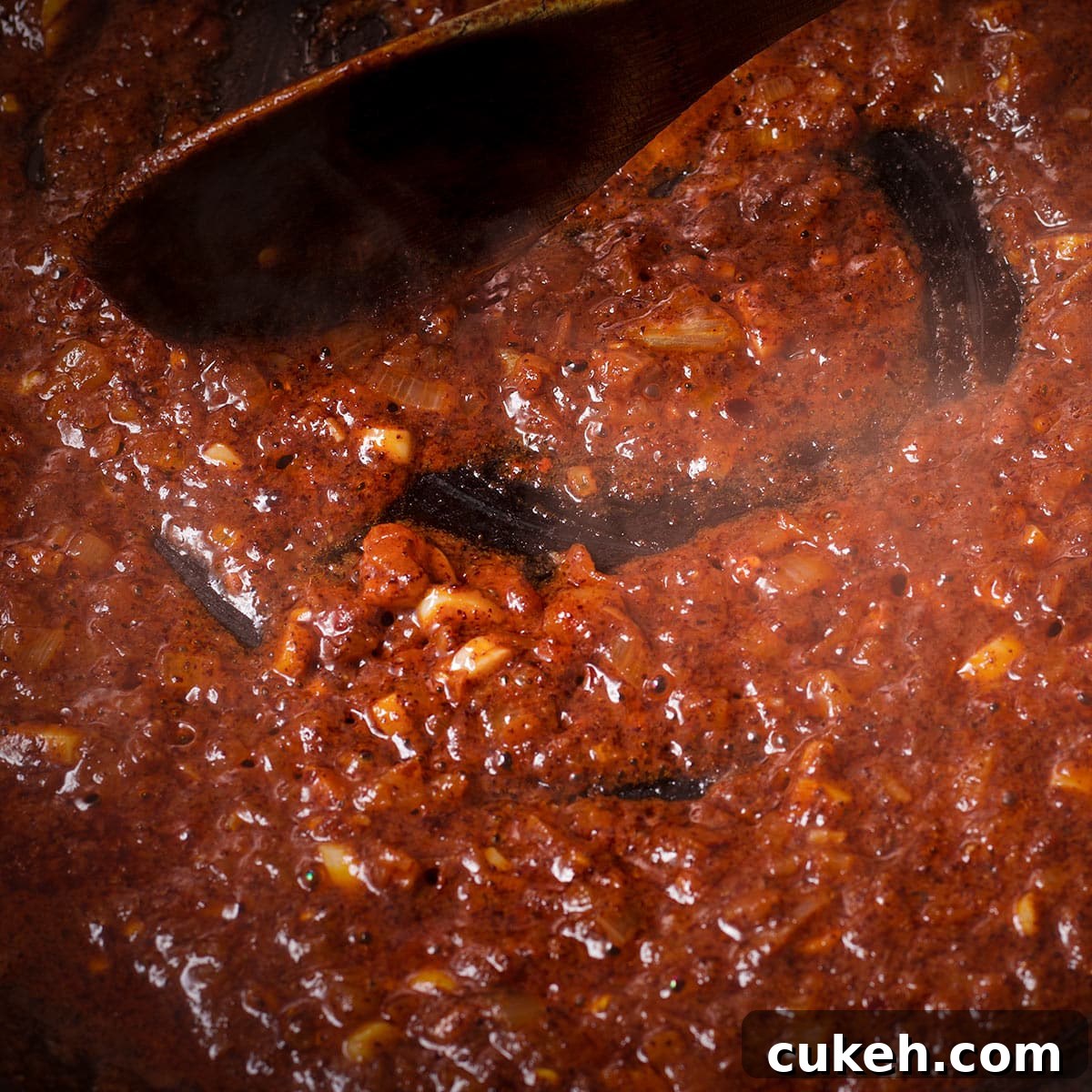 Using a spoon to stir the shallot and spice mixture after adding the wine to see if most of the liquid has evaporated.