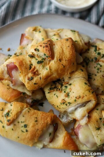 Stacked ham and cheese crescents on plate.