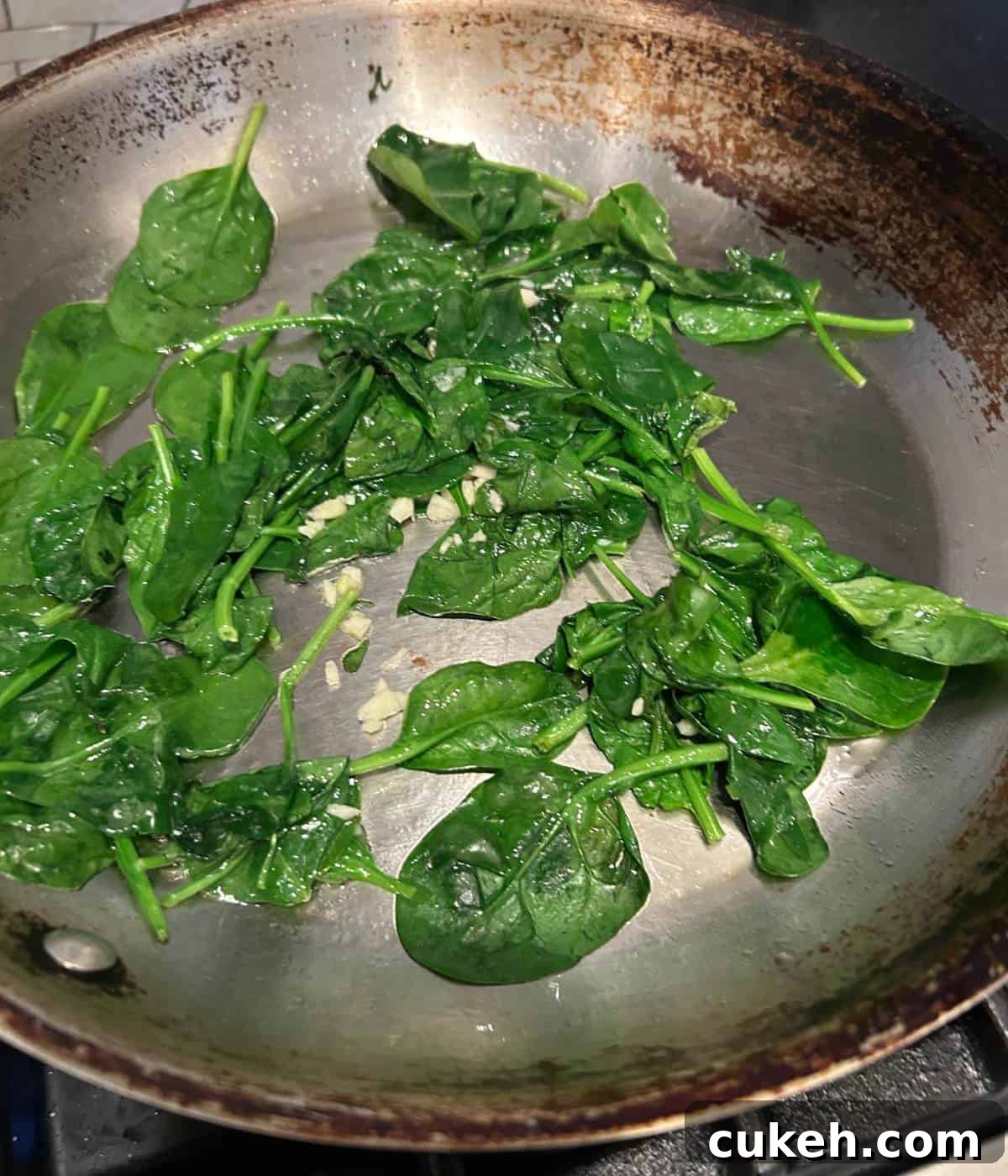 Spinach and garlic sautéing in pan.