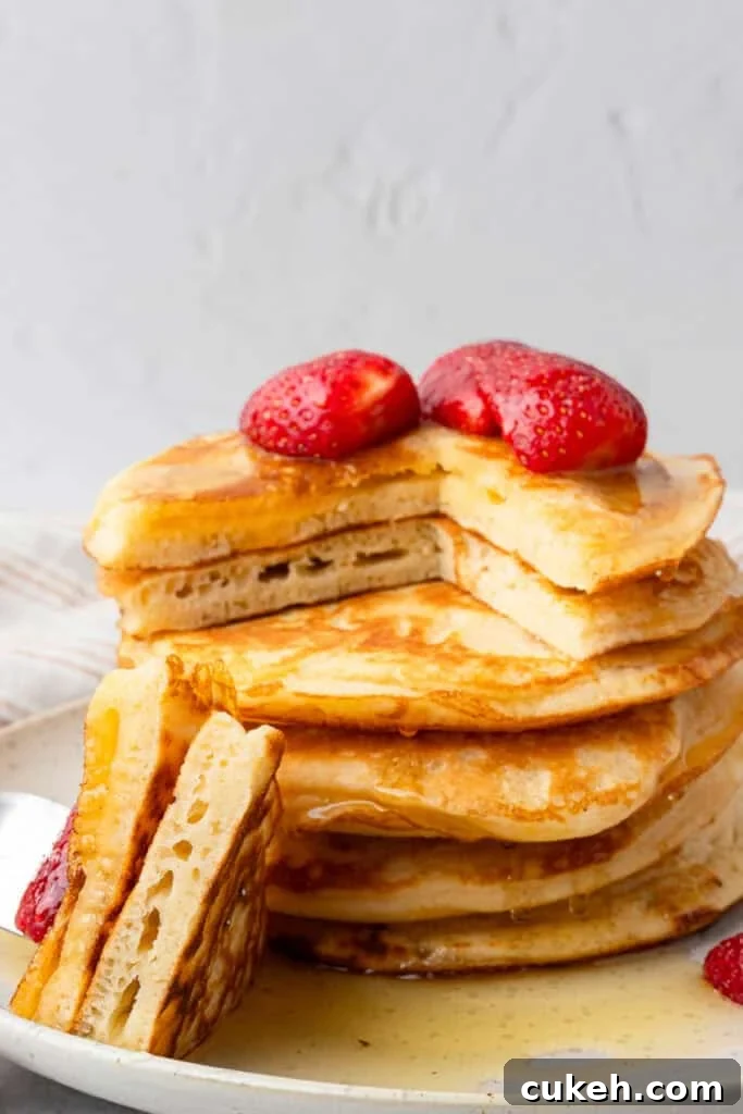 Gluten free pancakes in a  stack with a piece cut out and strawberries