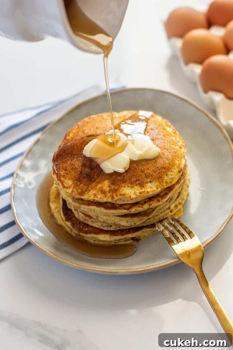 Short stack of pancakes with butter and syrup being drizzled on them