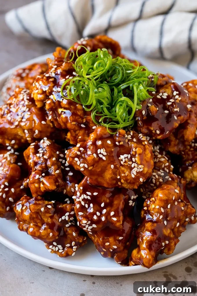 Korean fried chicken on a serving plate topped with curly green onions.