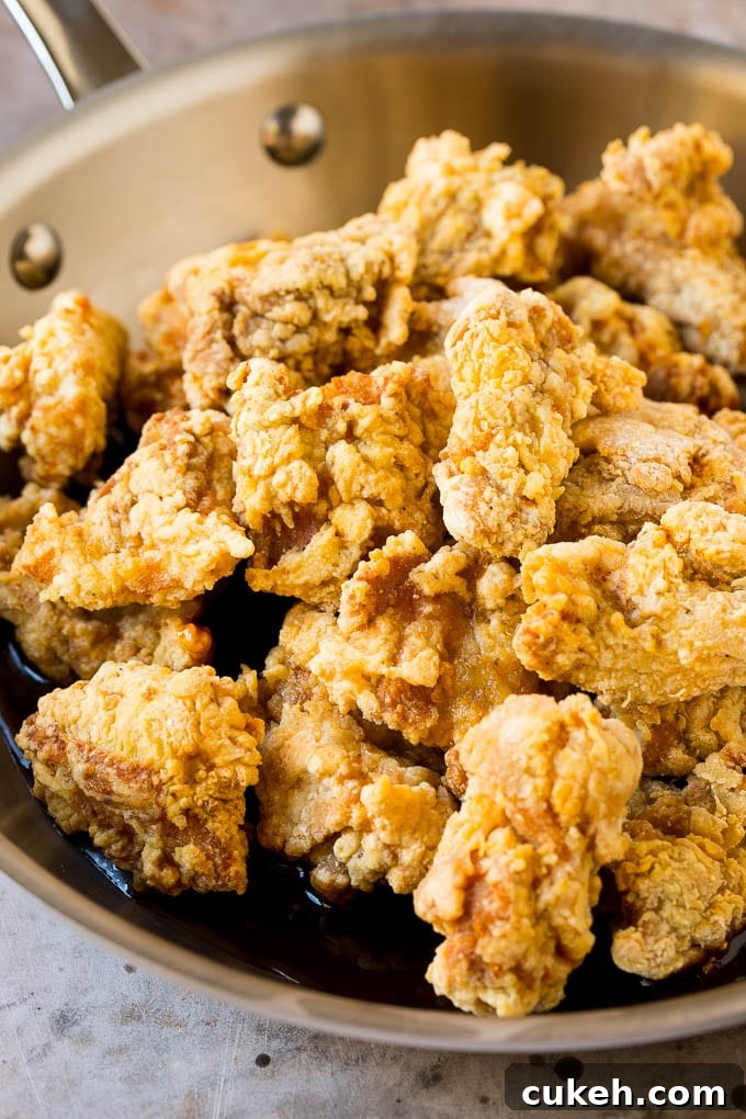 Fried chicken thigh pieces in a pan of sweet and savory Korean sauce.