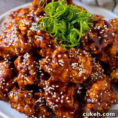 Korean fried chicken on a serving plate topped with curly green onions.