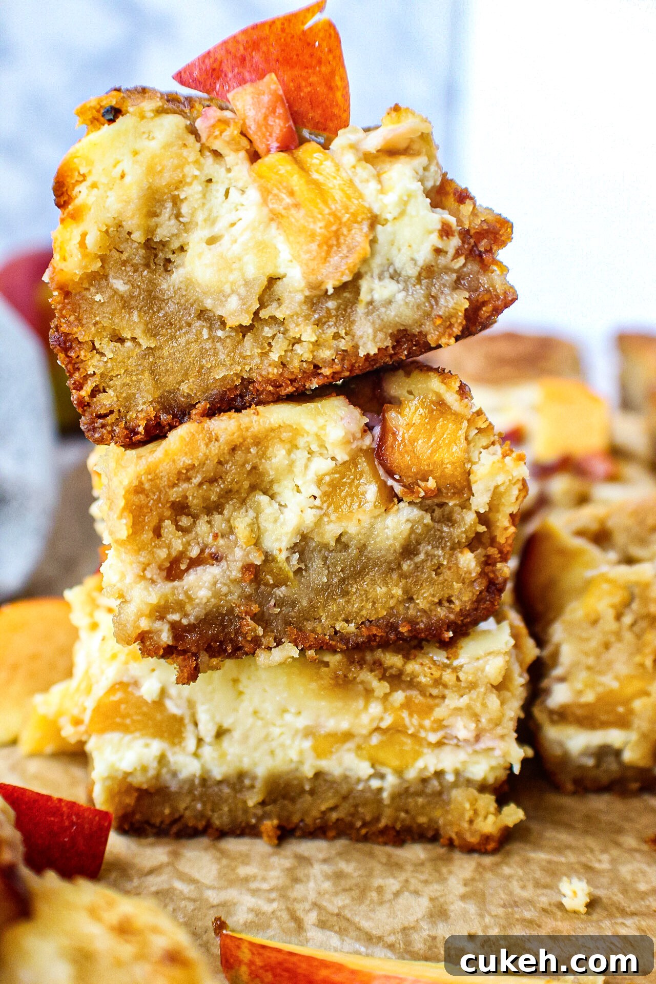 side angle close up shot of 3 peach cheesecake blondies stacked on top of each other.