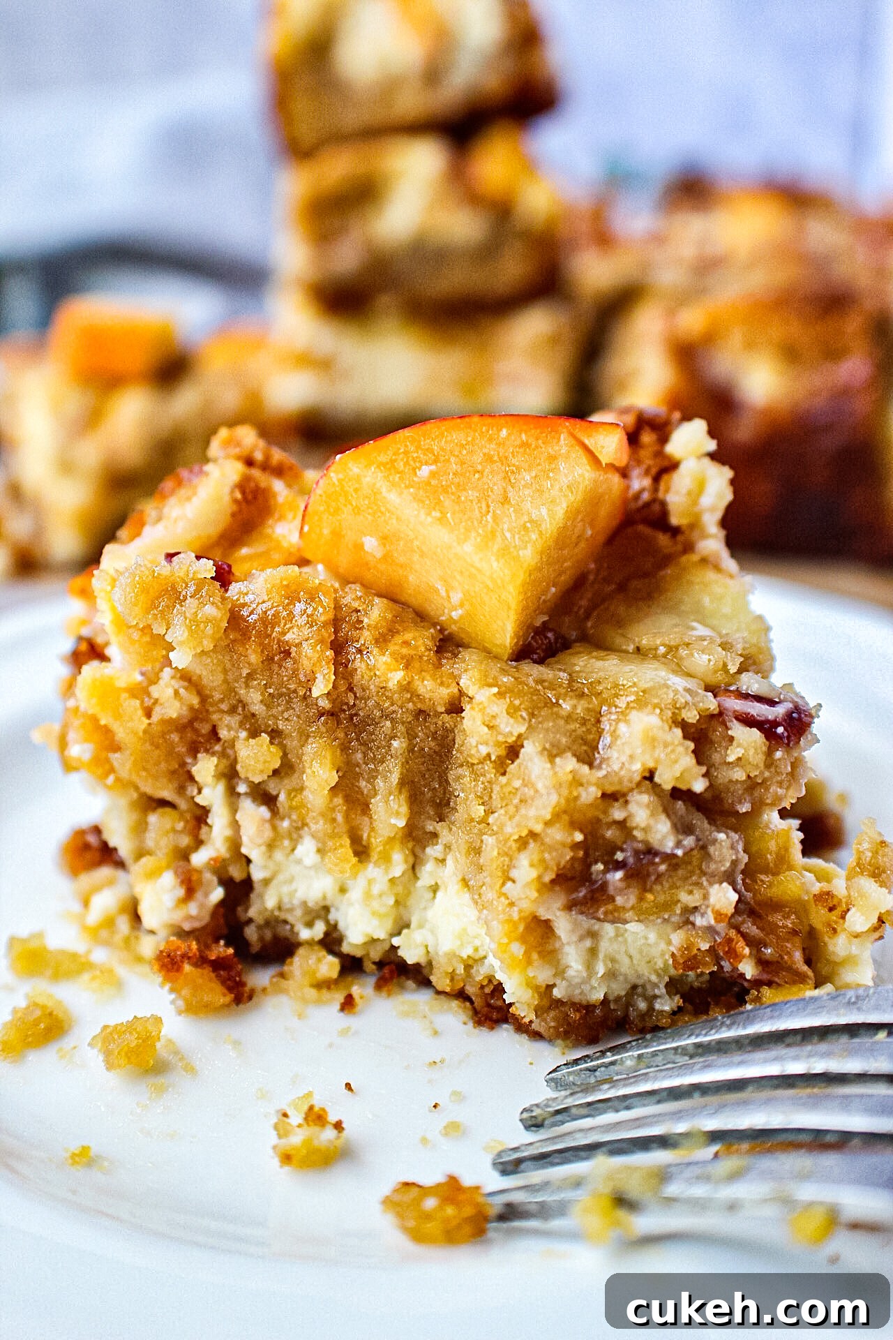 close up shot of peach cheesecake blondie on a small white plate with a bite taken out of it.