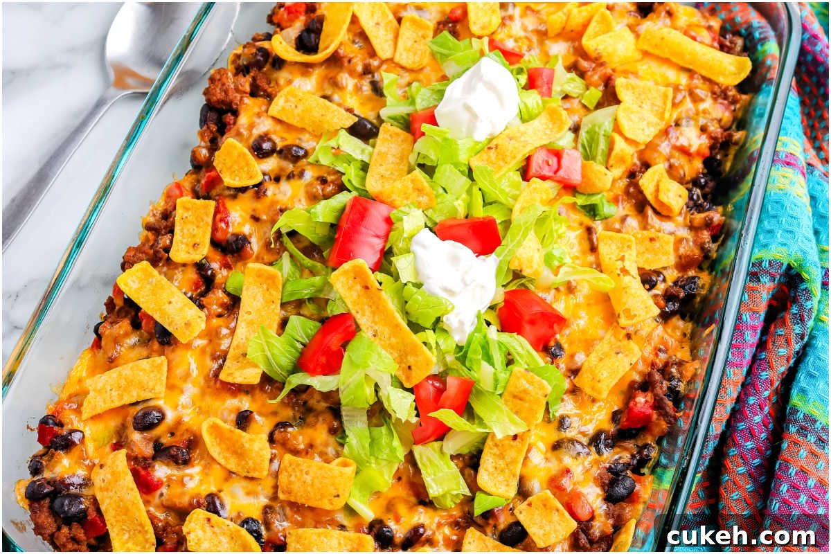 The finished casserole garnished with corn chips, sour cream, shredded lettuce, and tomatoes.