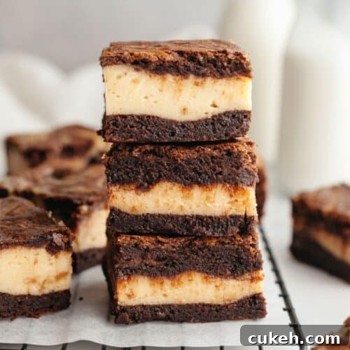 A stack of three peanut butter cheesecake brownies on parchment paper.