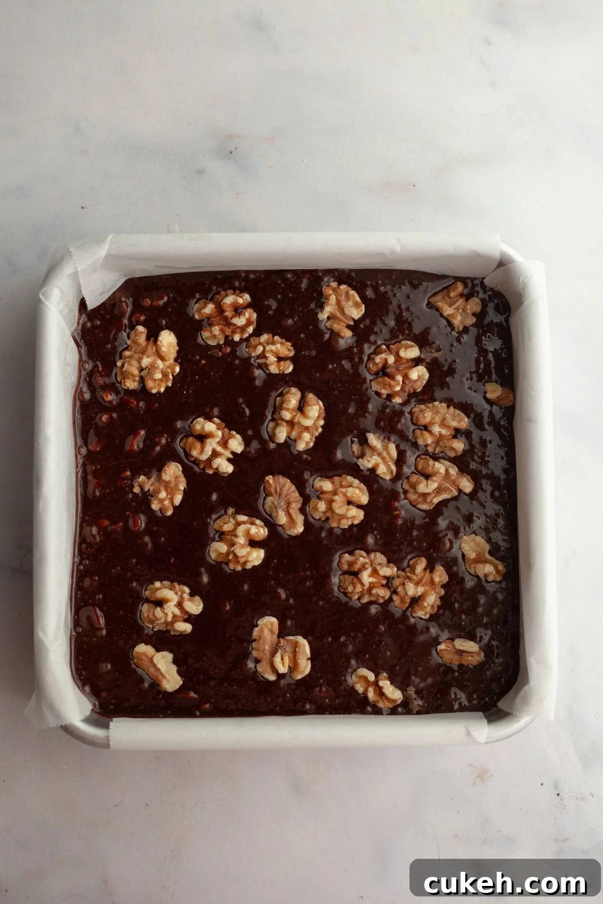 Unbaked walnut brownies in a square pan.