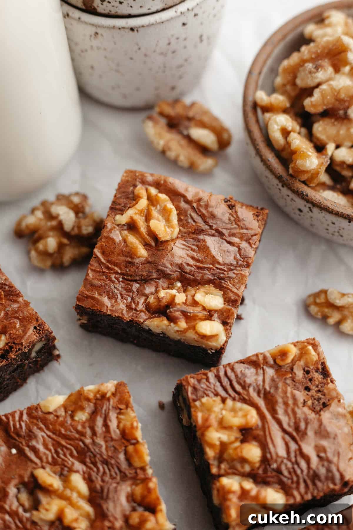 A close up of sliced fudgy walnut brownies on parchment paper.