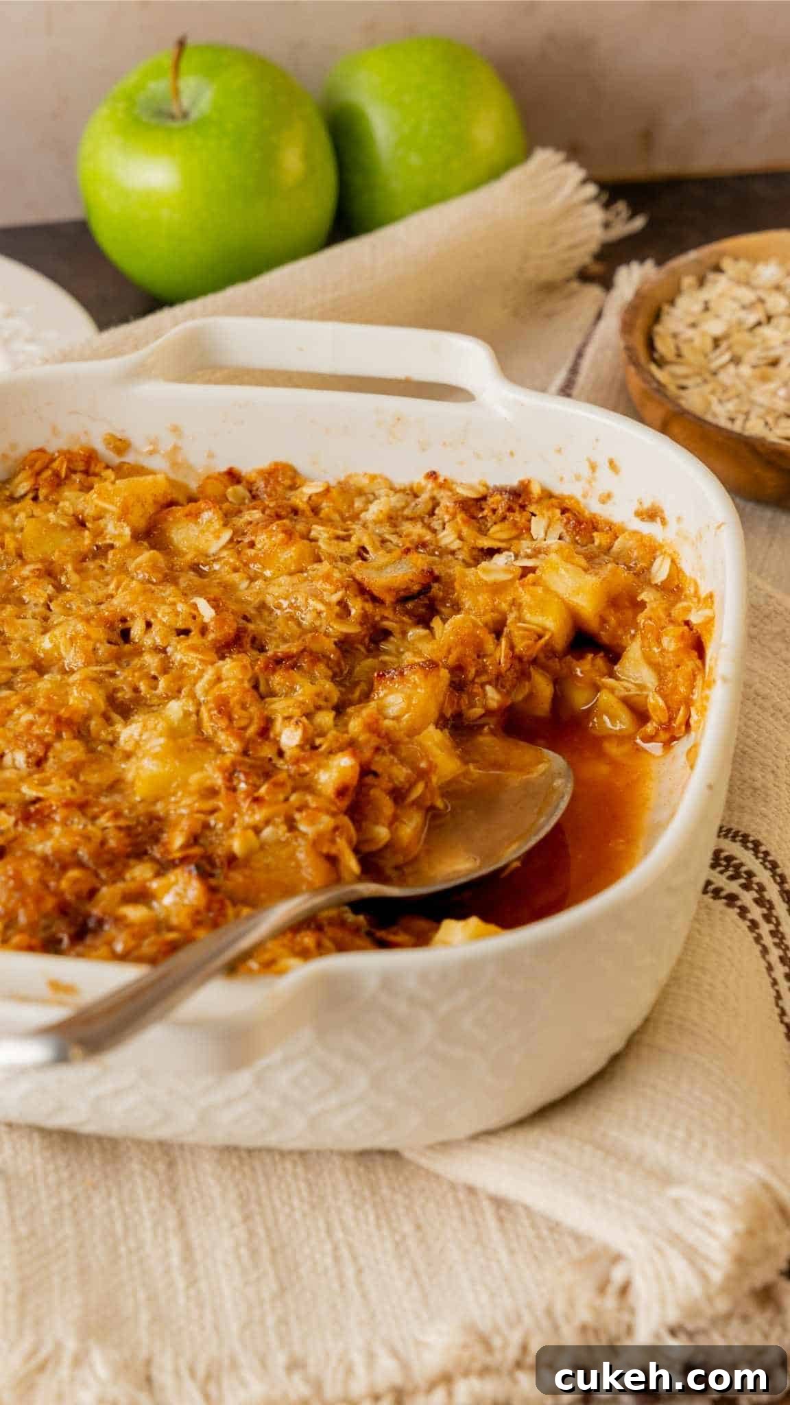 An 8 by 8 dish with apple crisp and a spoon for serving.