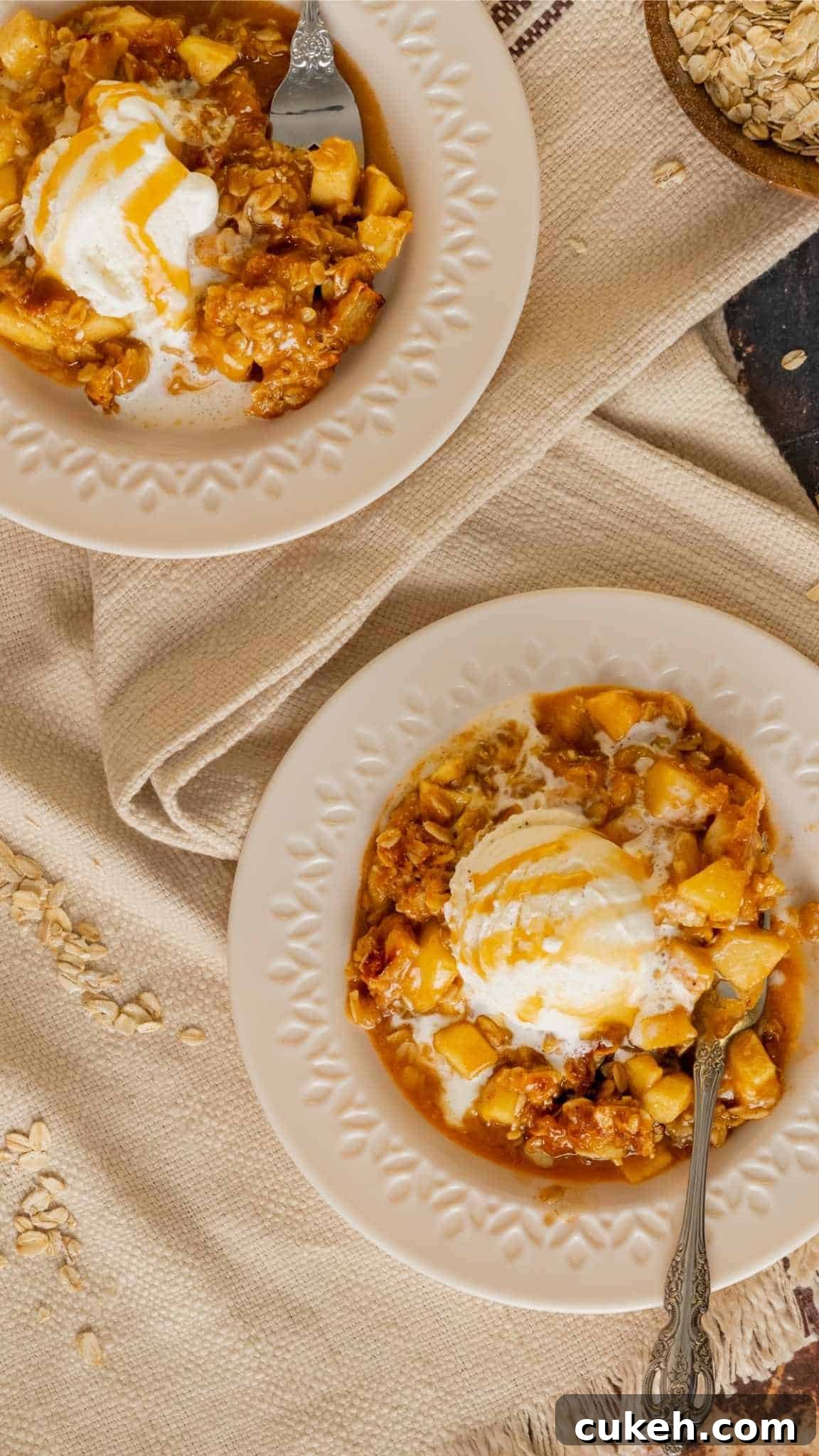 Two plates of apple crisp topped with vanilla ice cream with caramel drizzle.