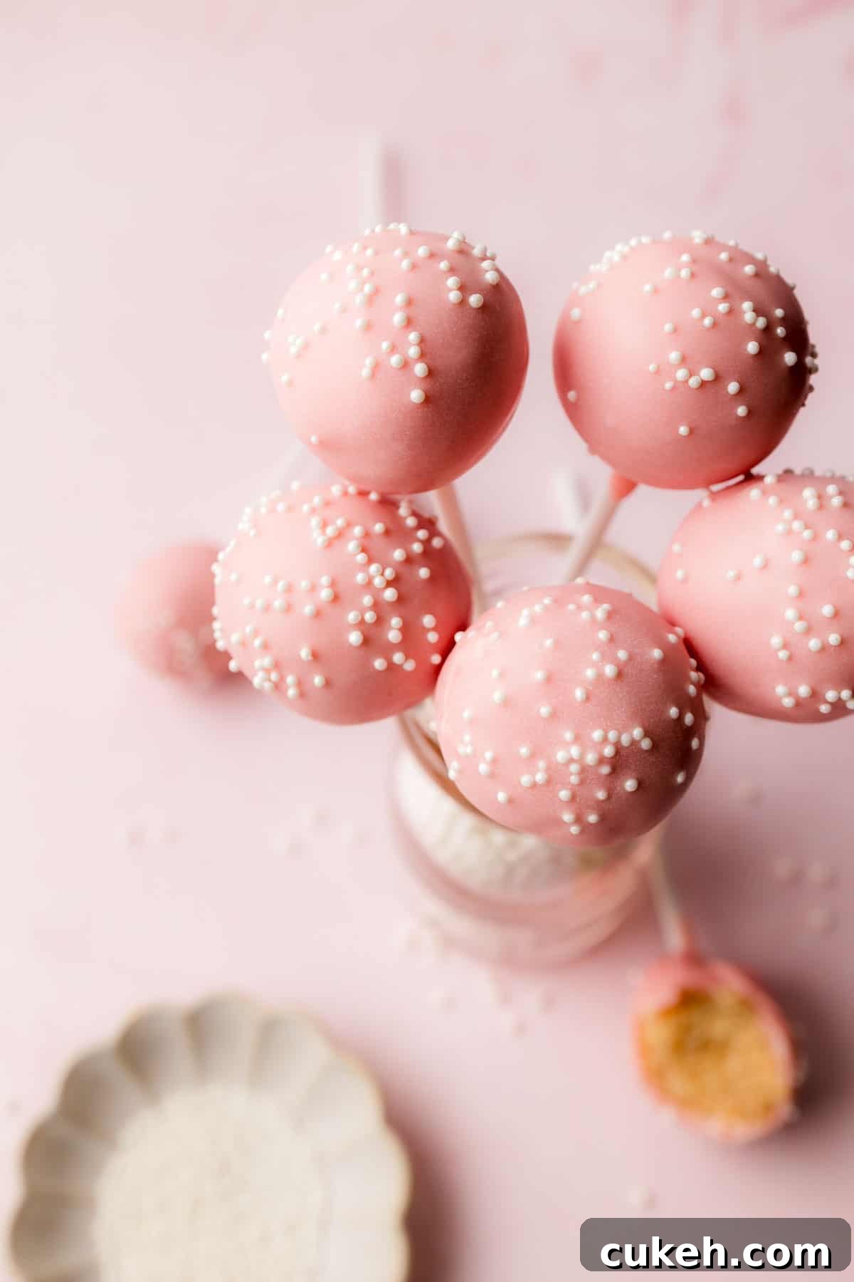 Starbucks-Style Gluten-Free Cake Pops Recipe 7 Pink gluten free cake pops with white pearl sprinkles in small vase.