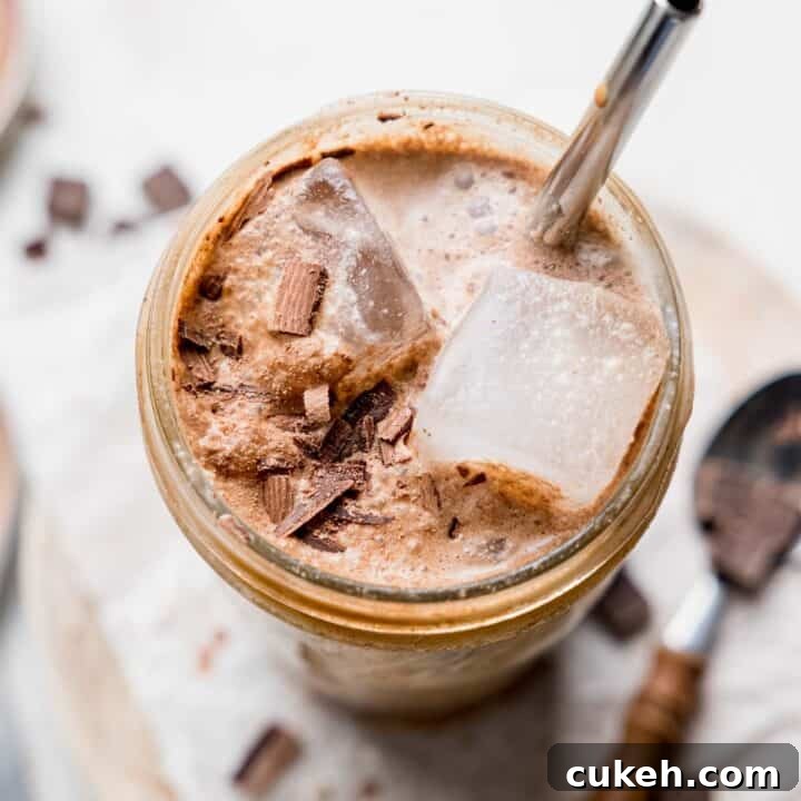 Chocolate shaken espresso in a large mason jar with ice and chocolate shavings.