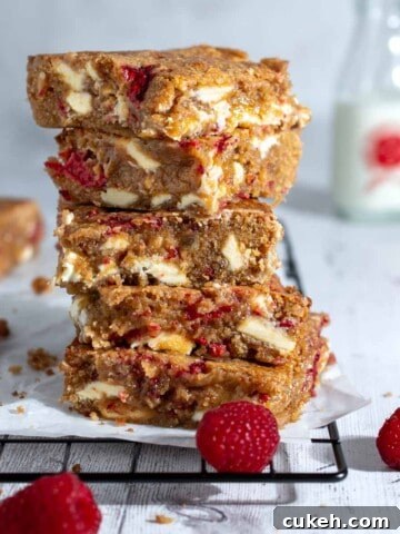 A stack of raspberry and white chocolate blondies on a black cooling rack.