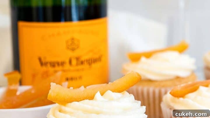 White cupcakes with champagne bottle in background.