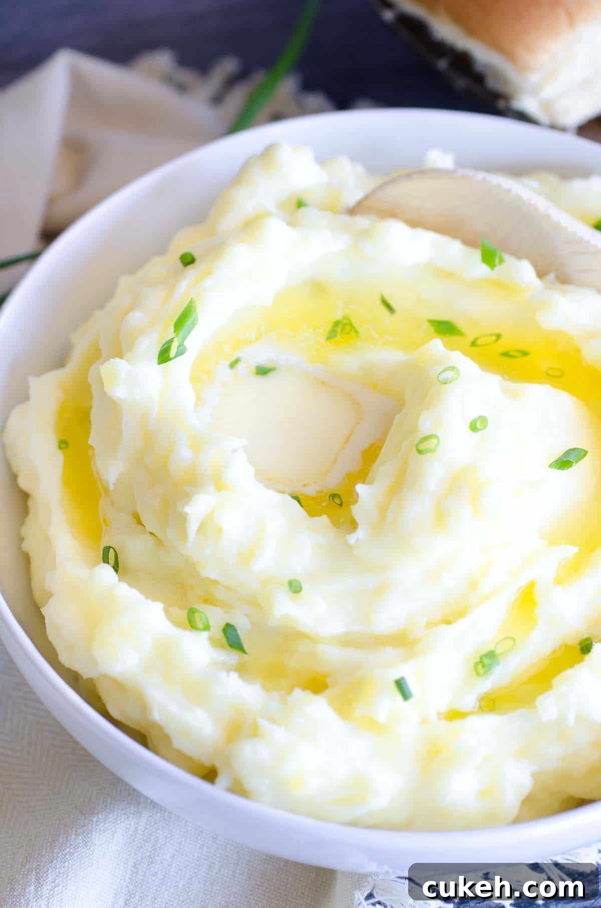 buttery mashed potatoes in a bowl with wooden spoon