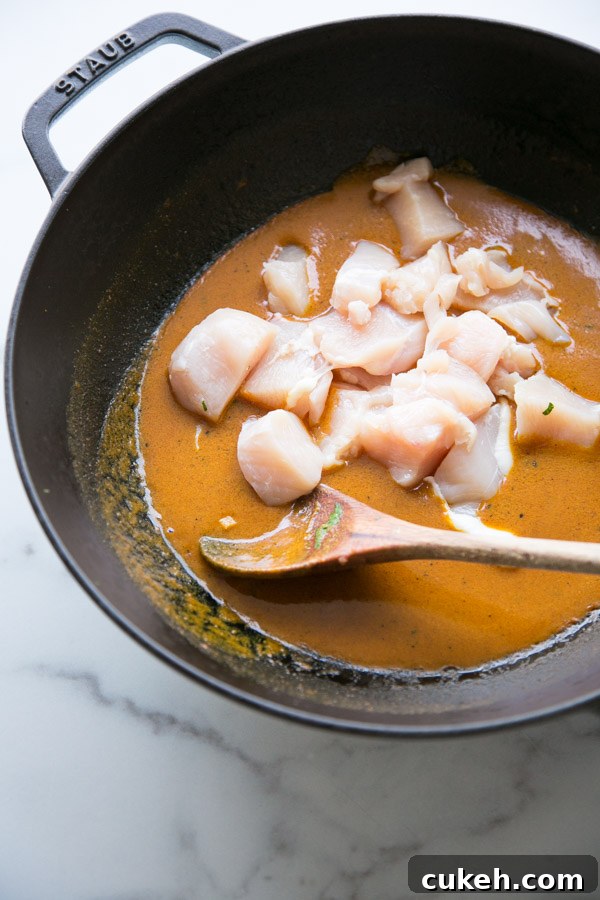 low fodmap curry sauce in a skillet with cubed raw chicken