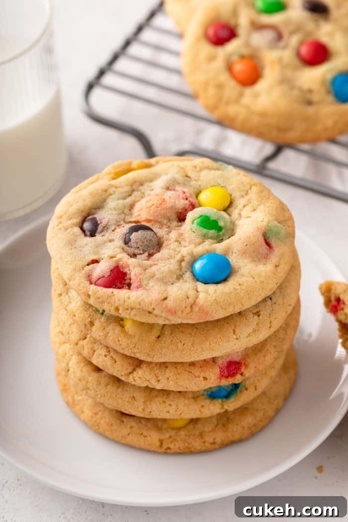 5 m&M cookies stacked on a white plate.