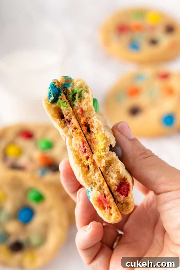 M&M cookie broken in half and being held up to the camera.