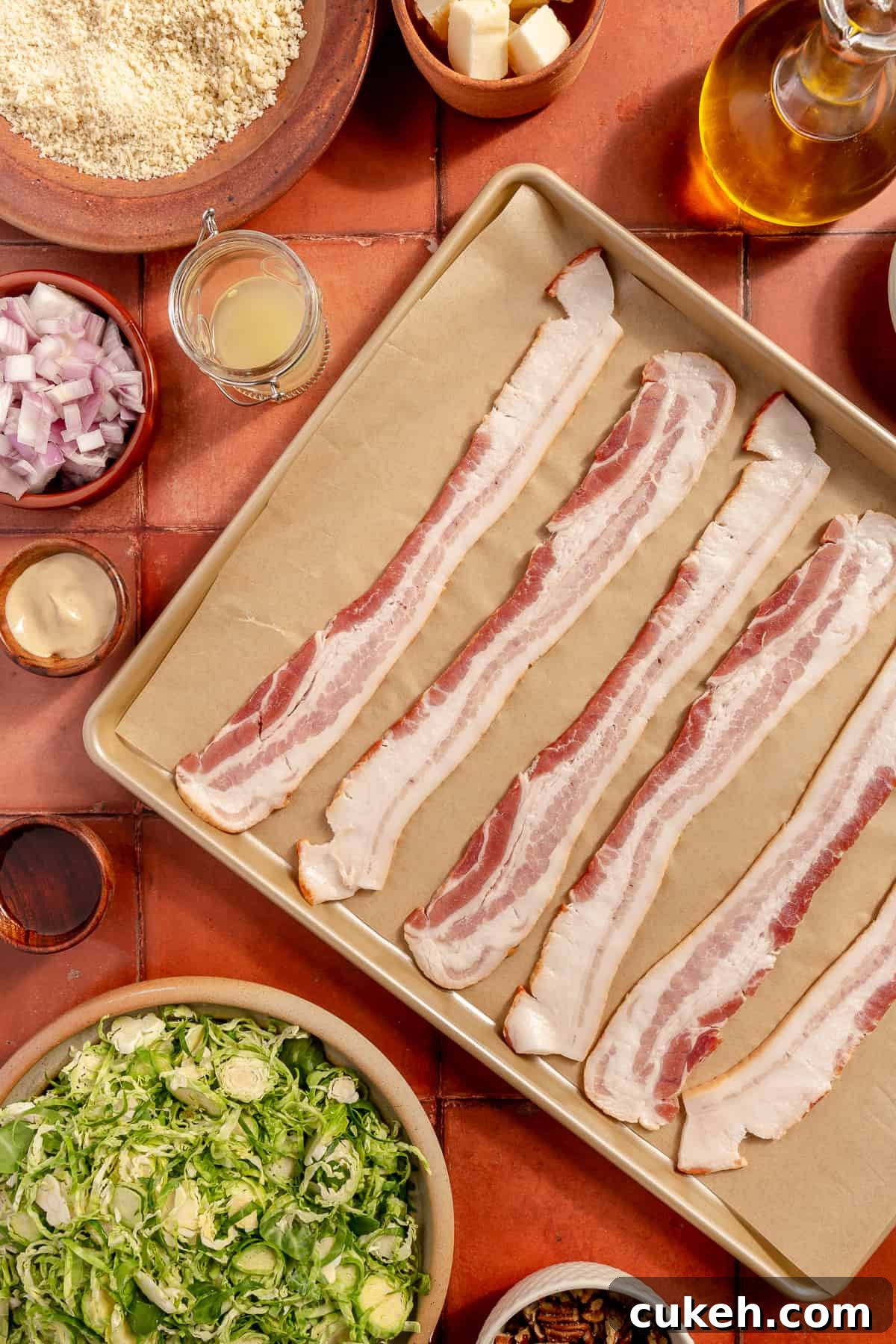 Raw bacon on sheet pan lined with parchment paper. Other ingredients scattered around.