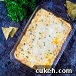 Buffalo Chicken Dip without Cream Cheese — Tangy, Cheesy Recipe 12 Buffalo chicken dip in a glass casserole dish, with tortilla chips sprinkled along the outside of the dish.