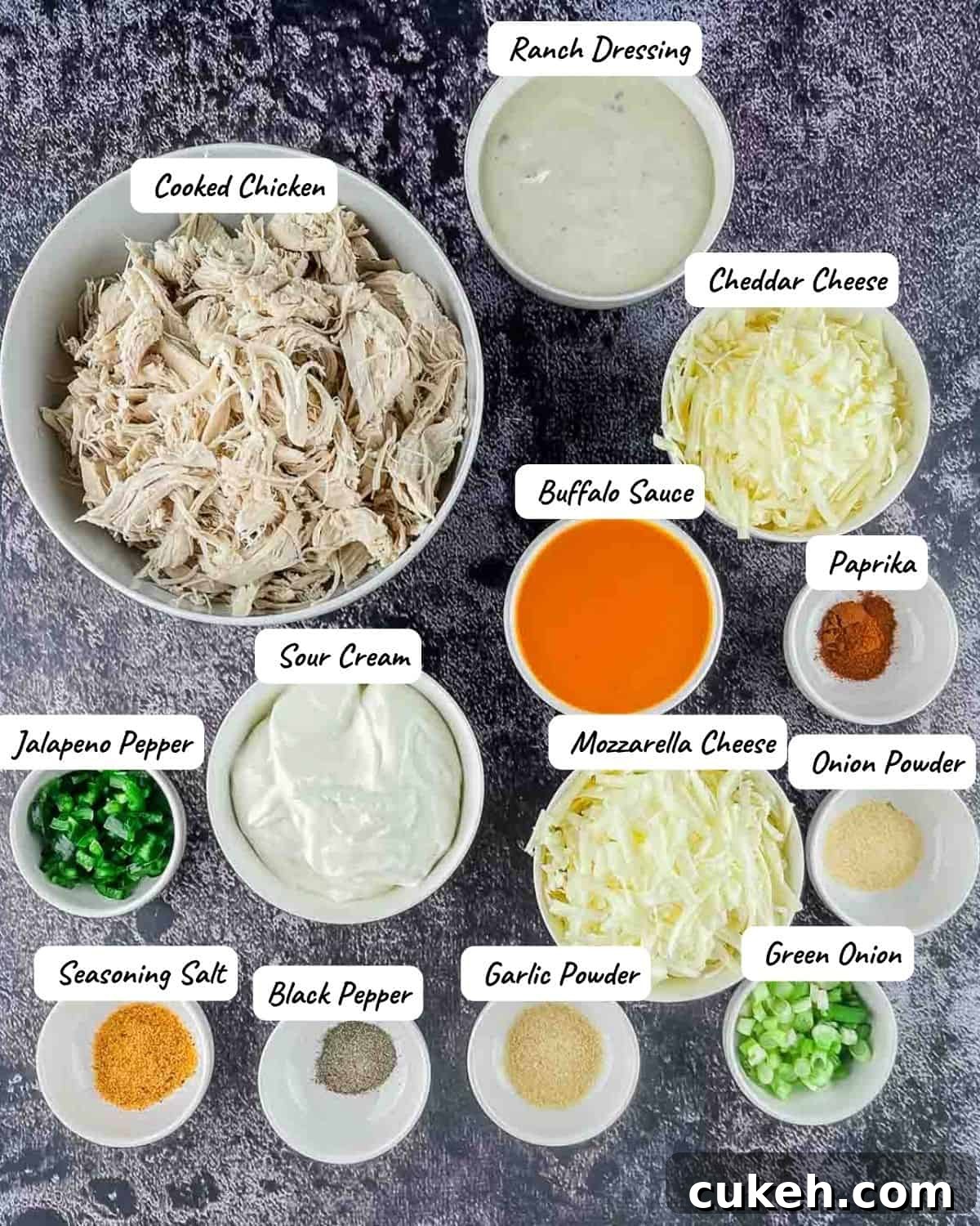 Buffalo Chicken Dip without Cream Cheese — Tangy, Cheesy Recipe 3 The ingredients needed to make the Buffalo Chicken Dip measured out and placed on a marled grey countertop.