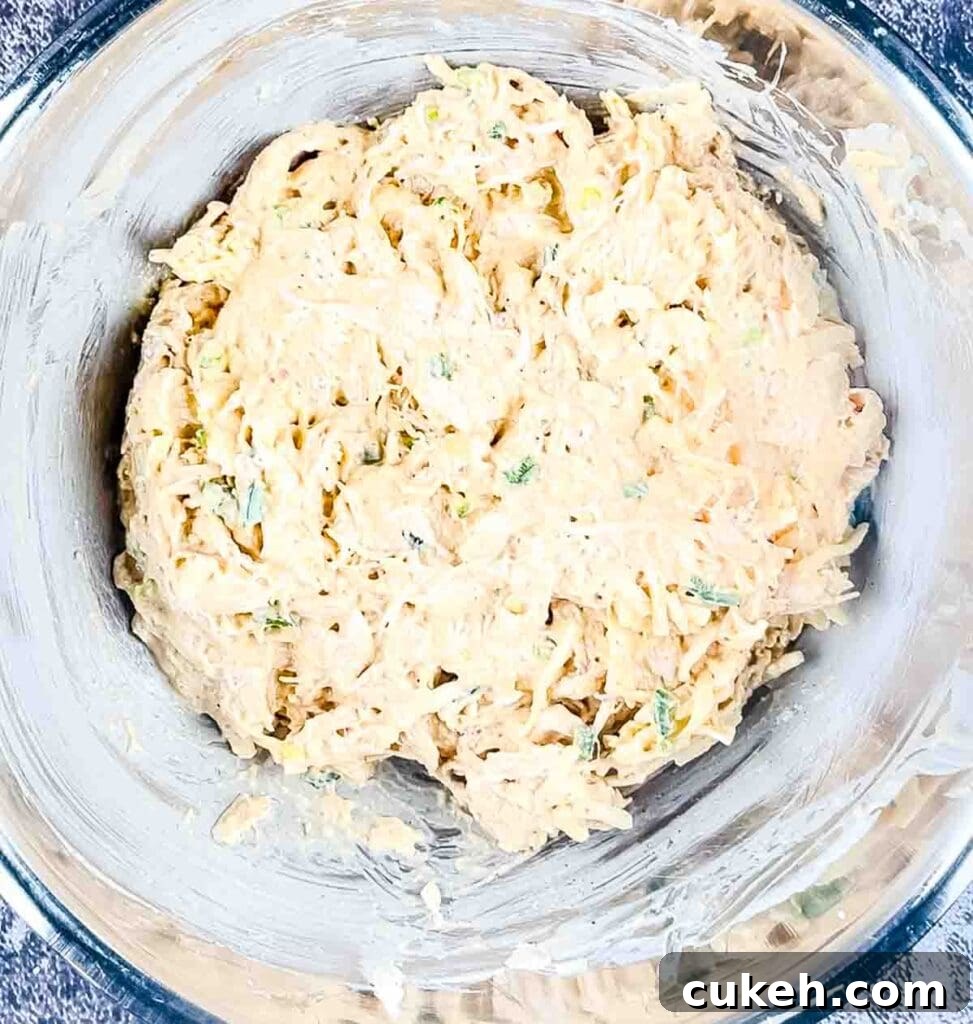 Buffalo Chicken Dip without Cream Cheese — Tangy, Cheesy Recipe 7 The cheese mixed with the chicken in a bowl with sour cream, seasoning, hot sauce, and ranch dressing.