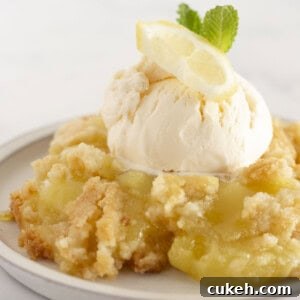 A serving of lemon dump cake on a plate with vanilla ice cream.