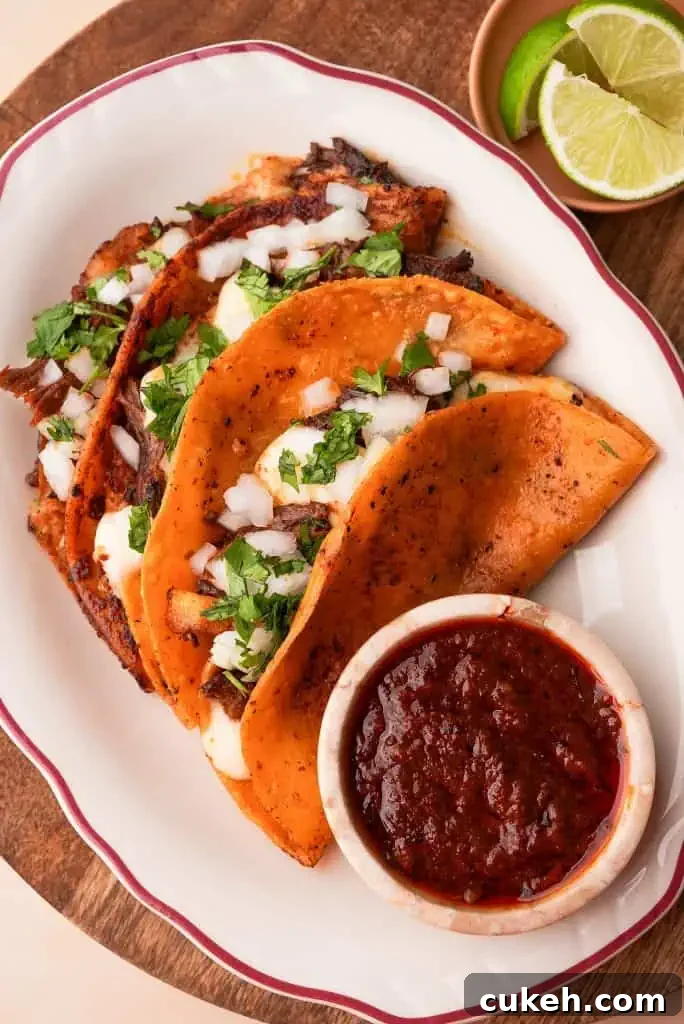 a plate of birria tacos with a side of consomé