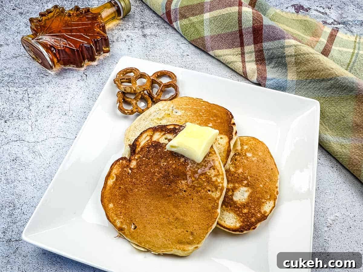 Pretzel pancakes with a bottle of maple syrup nearby.