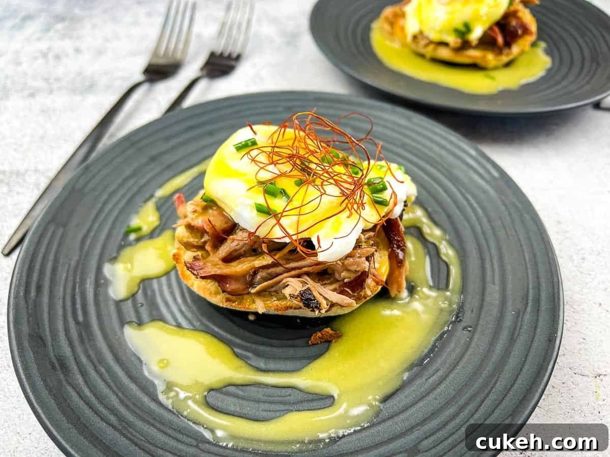 Two pulled pork eggs benedict on a plate with sauce.