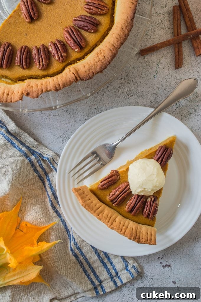 a slice of pumpkin pie with pecans served on a small white plate with silver forks for eating