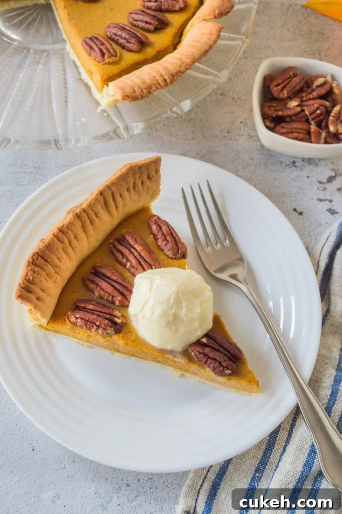 a slice of homemade pumpkin pie with pecans served on a small white plate with silver forks for eating