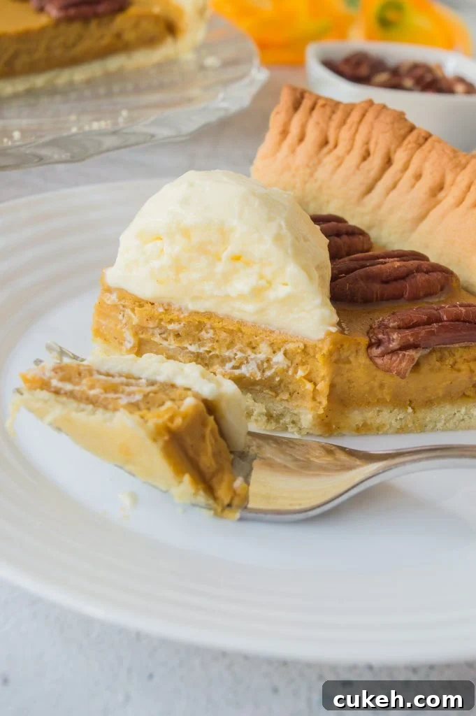 a slice of homemade pumpkin pie with pecans served on a small white plate with silver forks for eating