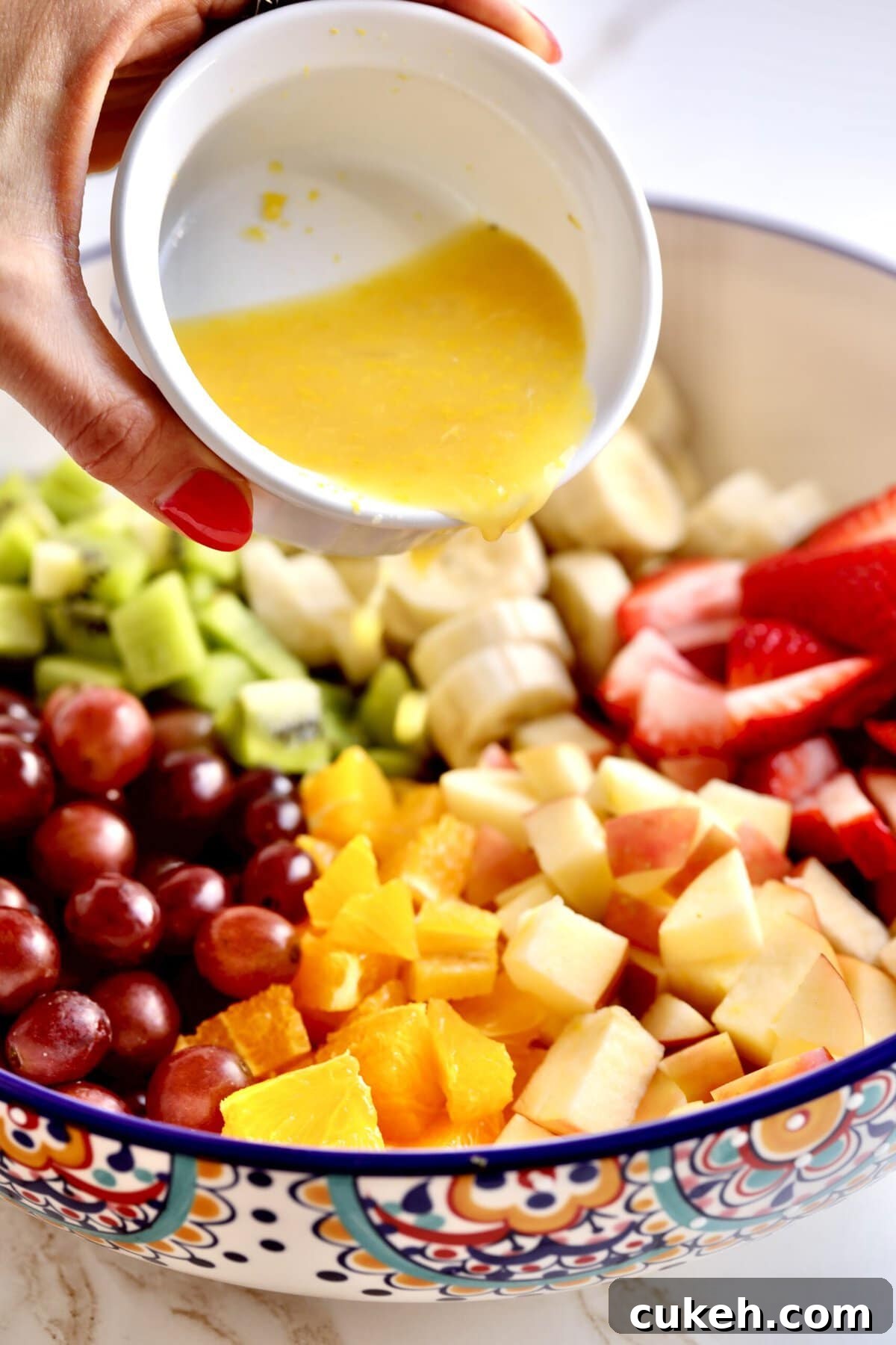 How to make Italian fruit salad recipe- adding the marinade to the fruit in the bowl.