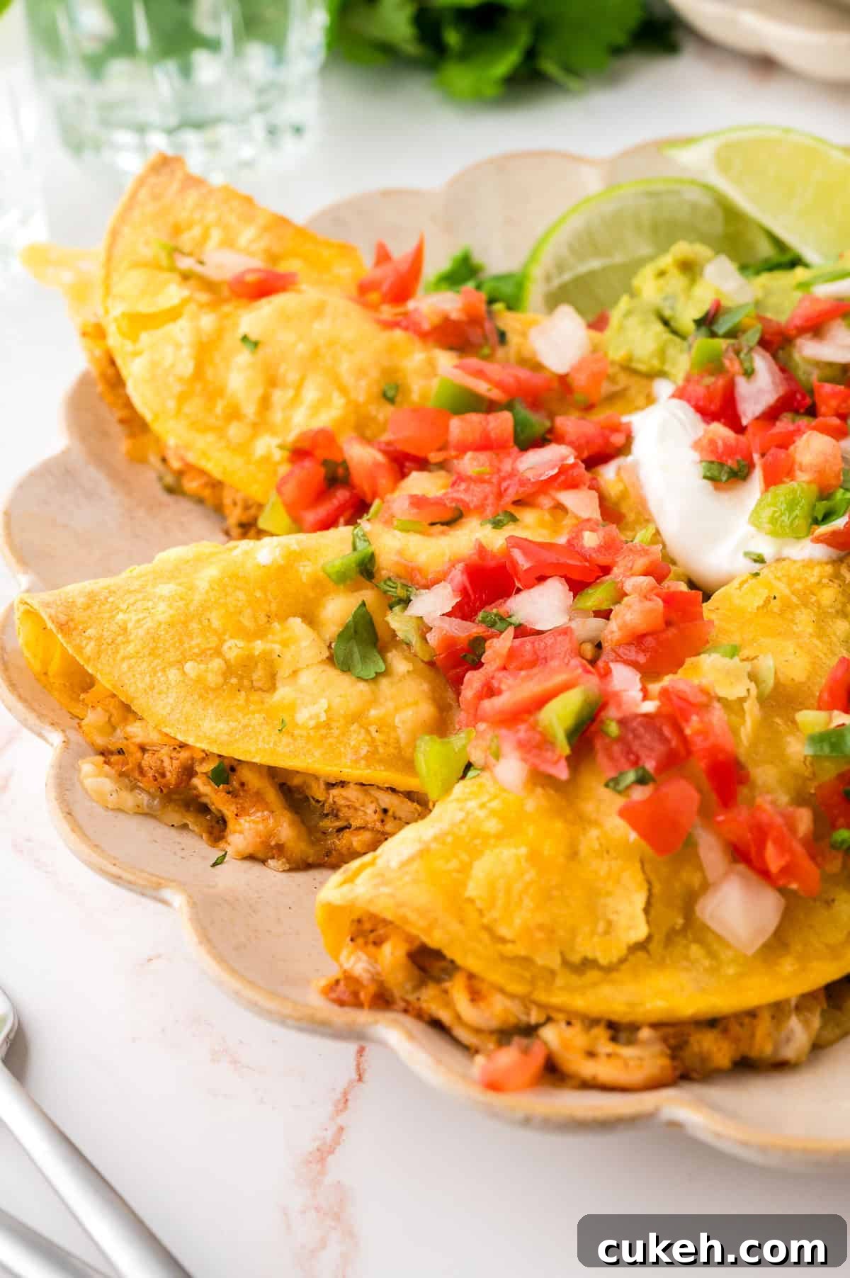 Three chicken tacos topped with pico de gallo and sour cream.