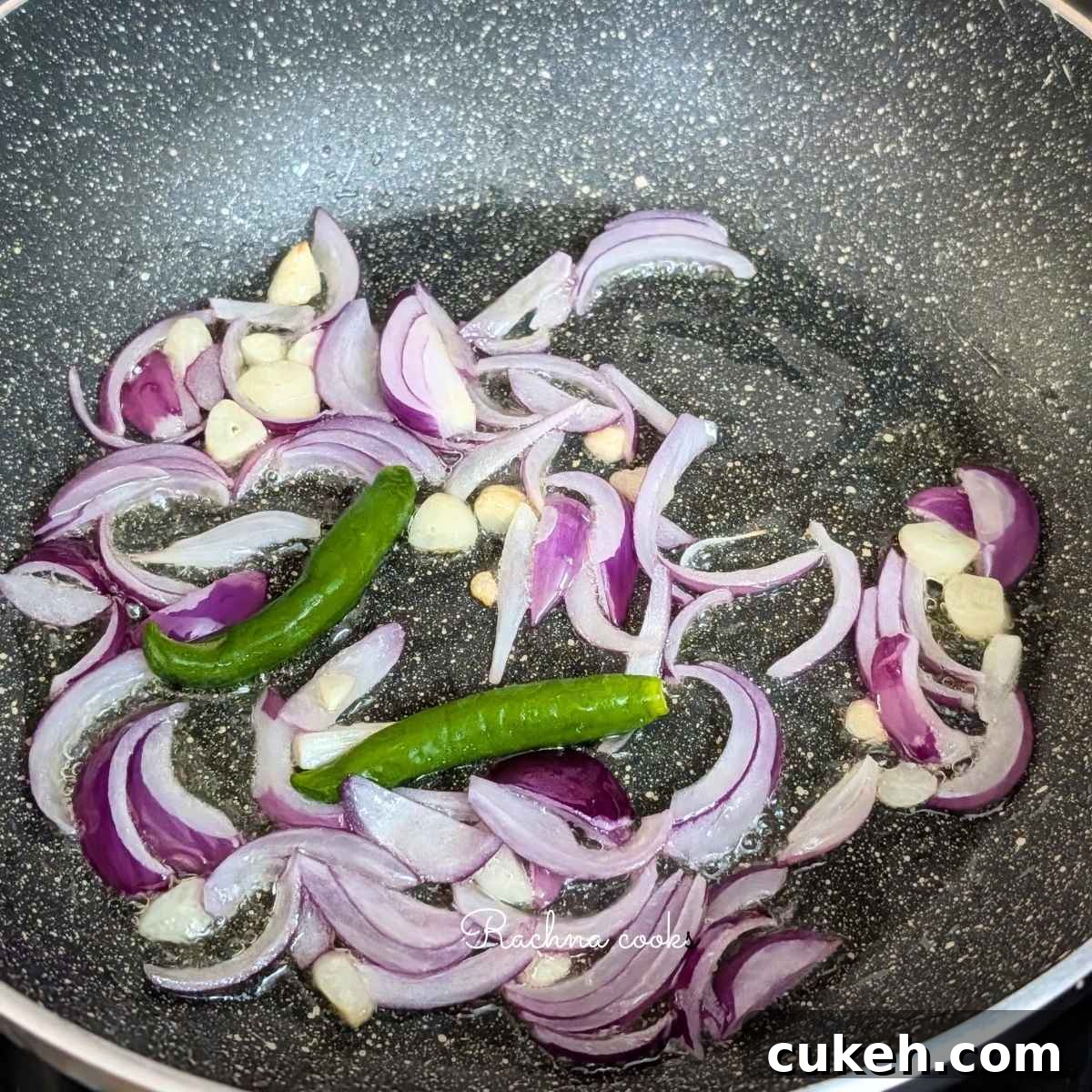 Sliced onion, garlic and green chillies added to oil in a pan