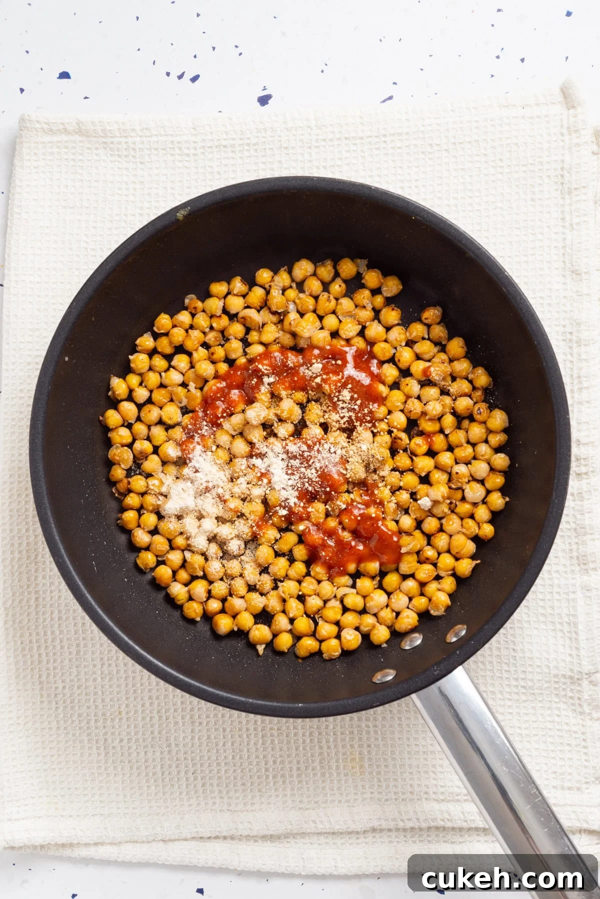 An overhead image of cooking chickpeas in a skillet.