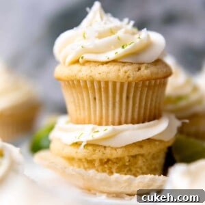 Stacked coconut lime cupcakes topped with coconut cream cheese frosting.