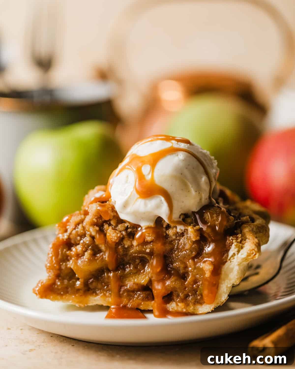a slice of salted caramel dutch apple pie on a plate with ice cream and salted caramel sauce on top. 