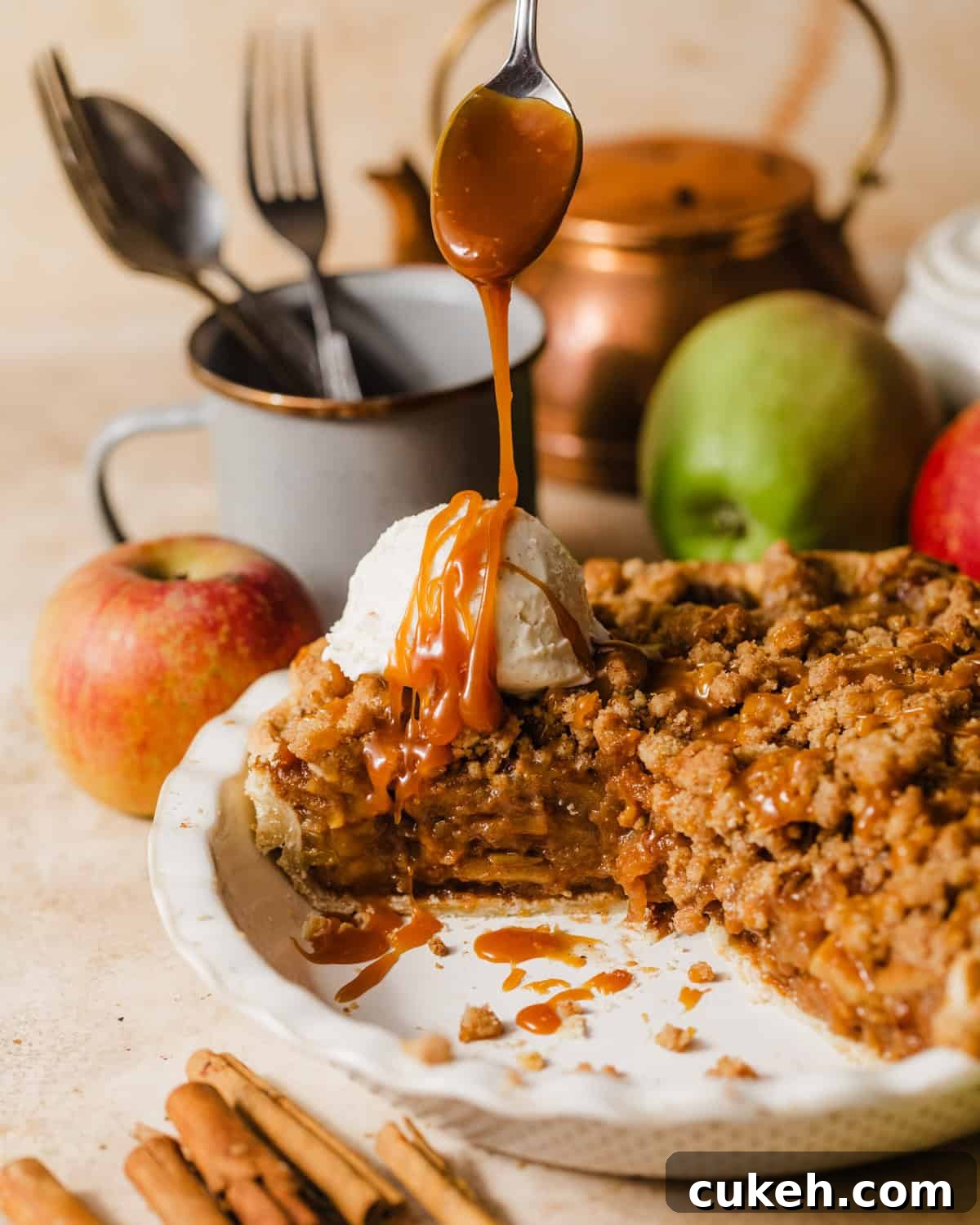 salted caramel dutch apple pie in a pie dish with ice cream and salted caramel sauce being drizzled on top. 