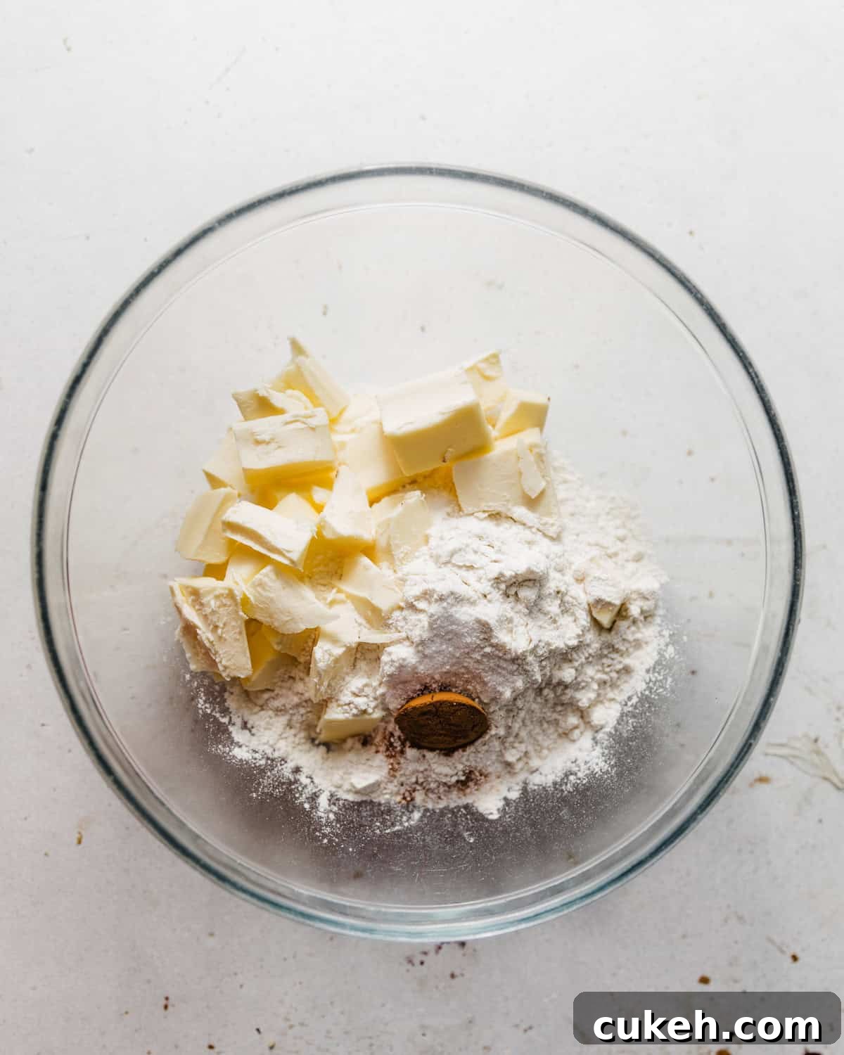 dry ingredients for pie crust mixed together in a bowl with cold butter.