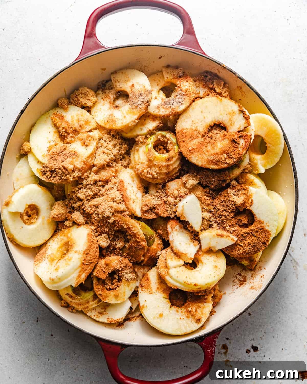 apples covered in sugar and spices in a large pan to make the apple pie filing.