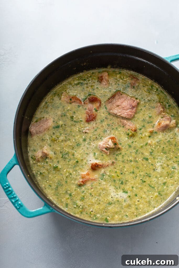 Pork added back into pot with blended sauce with the sauce and being simmered together. 