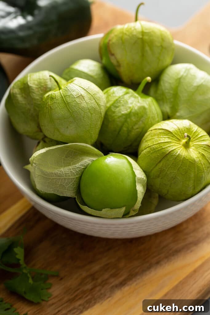 A white bowl filled with fresh tomatillos in their husk