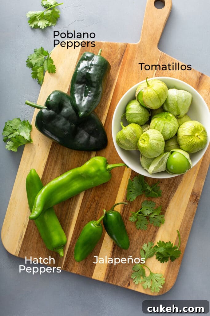 Fresh tomatillos, fresh poblano peppers, hatch peppers and jalapeños on a cutting board.