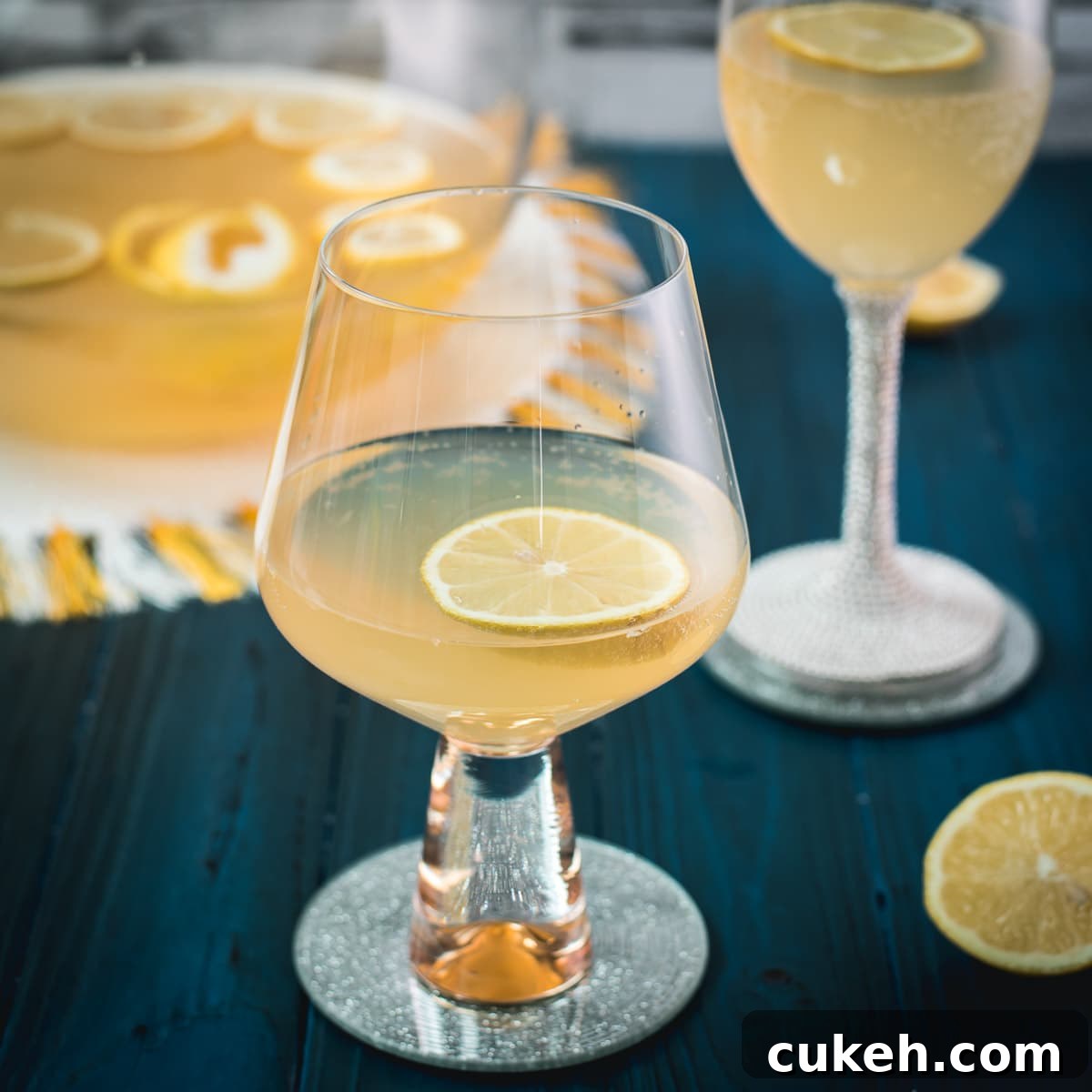 Two glassed filled with lemon punch. Garnished with a lemon slice and placed on a mirror coaster.