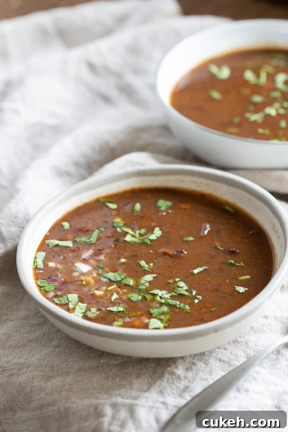 side view of a bowl of vegan Instant Pot black bean soup on a white cloth napkin
