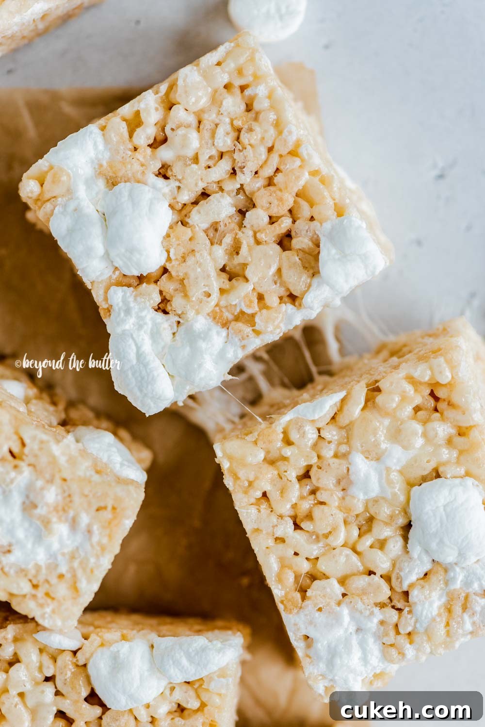 Overhead image of just cut rice krispie treats on parchment paper with a knife placed to the right | All Images © Beyond the Butter™